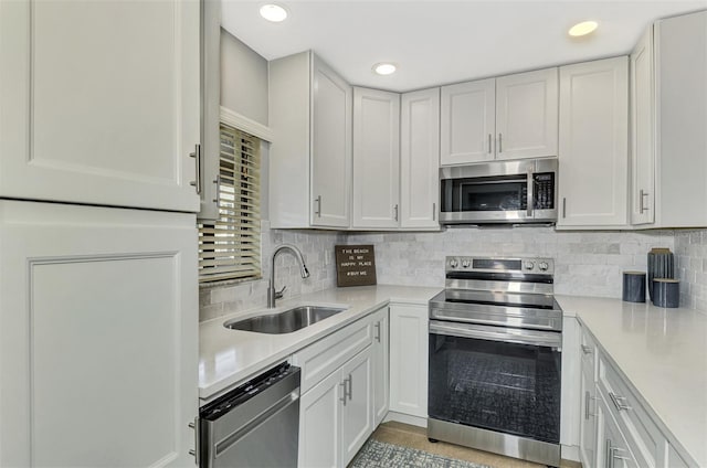 kitchen featuring light tile patterned floors, white cabinetry, stainless steel appliances, tasteful backsplash, and sink