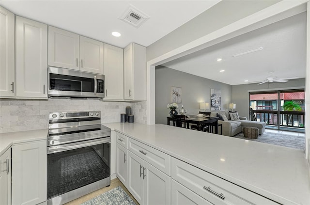 kitchen with ceiling fan, backsplash, stainless steel appliances, and white cabinetry