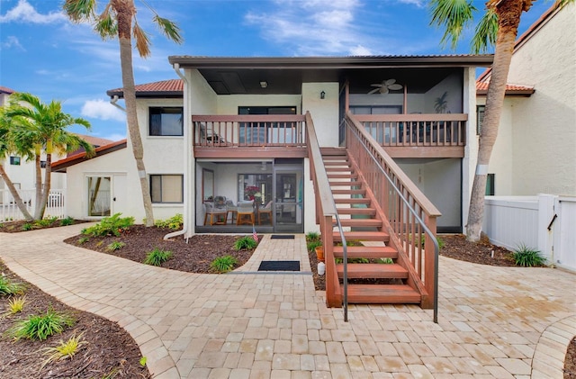 rear view of property with ceiling fan, a sunroom, and a balcony