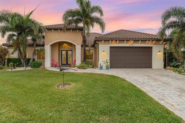 mediterranean / spanish home with french doors, a garage, and a lawn