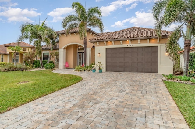 mediterranean / spanish home featuring a garage and a front lawn