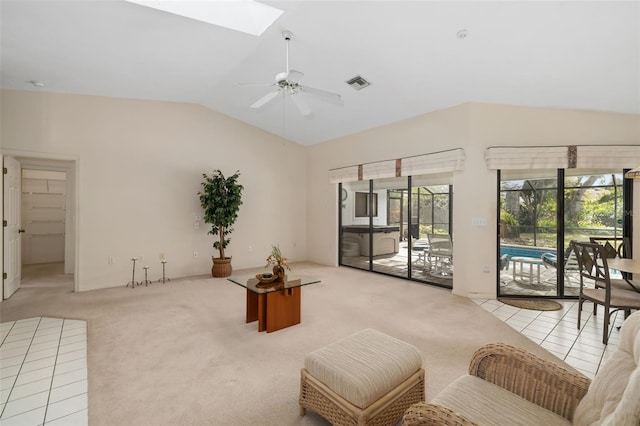 living room with ceiling fan, light colored carpet, and lofted ceiling with skylight