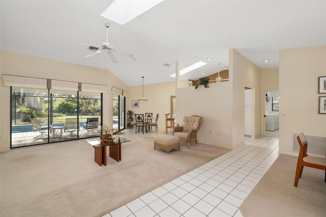 living room featuring ceiling fan, light colored carpet, washer / dryer, and vaulted ceiling with skylight