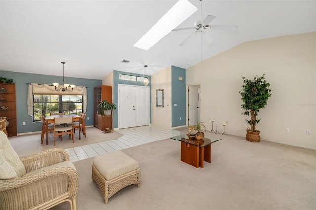 tiled living room with vaulted ceiling with skylight and ceiling fan with notable chandelier