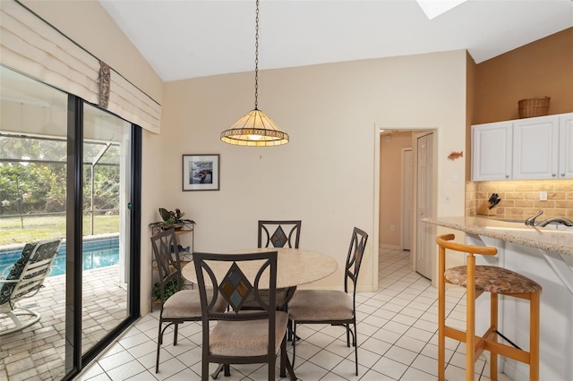 tiled dining room featuring vaulted ceiling with skylight