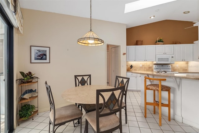 dining space with light tile patterned floors and lofted ceiling with skylight