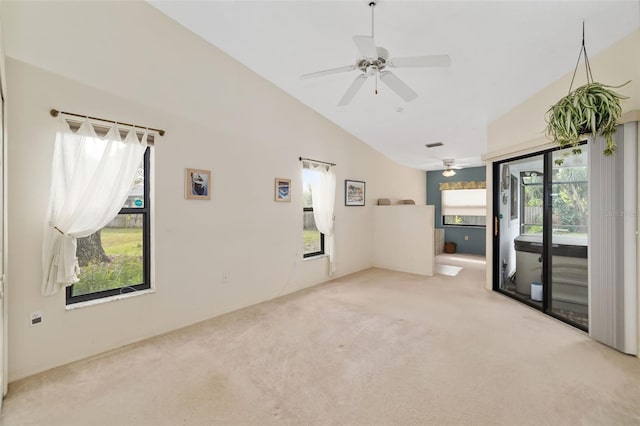 empty room featuring ceiling fan, a wealth of natural light, lofted ceiling, and light colored carpet