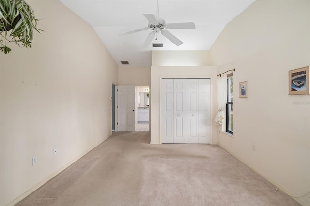 unfurnished bedroom featuring lofted ceiling, light colored carpet, ceiling fan, and a closet