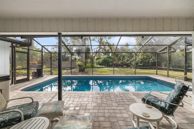 view of pool featuring glass enclosure, a lawn, and a patio