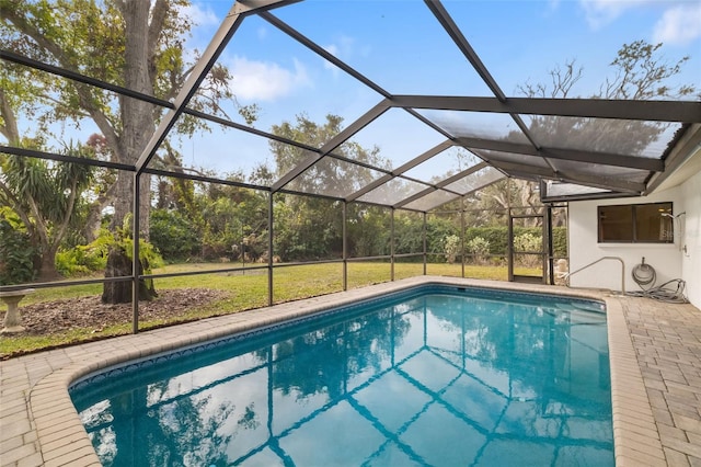 view of pool featuring glass enclosure, a patio area, and a lawn