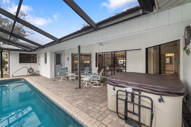 back of property featuring glass enclosure, ceiling fan, a patio area, and a pool with hot tub