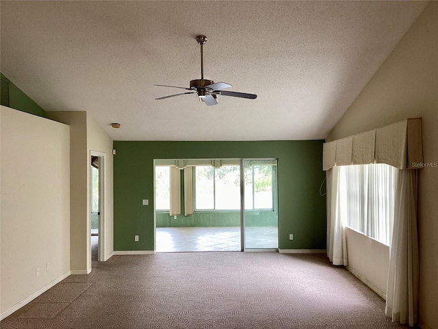 spare room featuring a textured ceiling, ceiling fan, vaulted ceiling, and light colored carpet