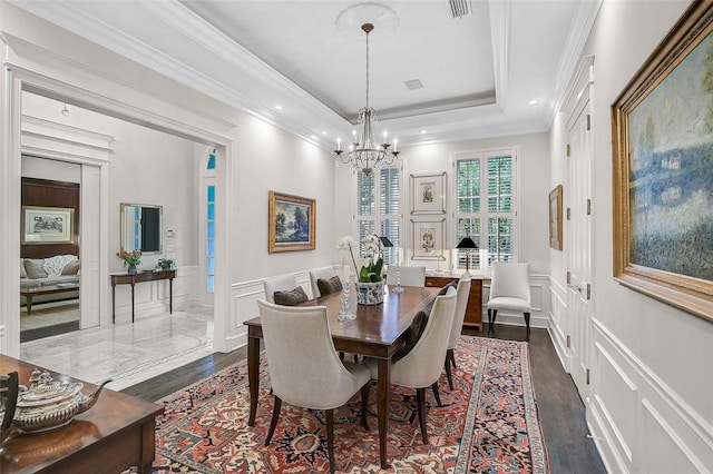 dining room featuring visible vents, ornamental molding, wainscoting, a decorative wall, and a raised ceiling