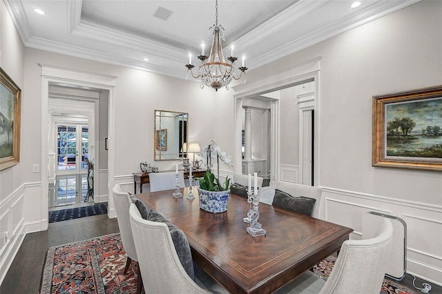 dining room featuring a raised ceiling, a decorative wall, dark wood-style floors, and a wainscoted wall