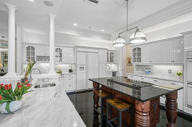 kitchen featuring a sink, decorative columns, paneled fridge, and black electric cooktop