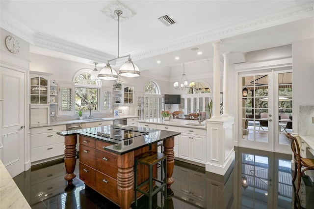 kitchen with visible vents, white cabinetry, decorative columns, and a sink