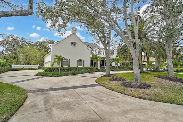 view of front of property featuring stucco siding, a front yard, and curved driveway