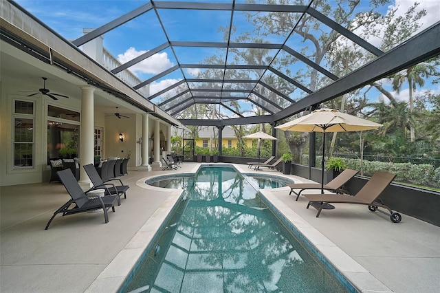 outdoor pool featuring glass enclosure, a patio area, and ceiling fan