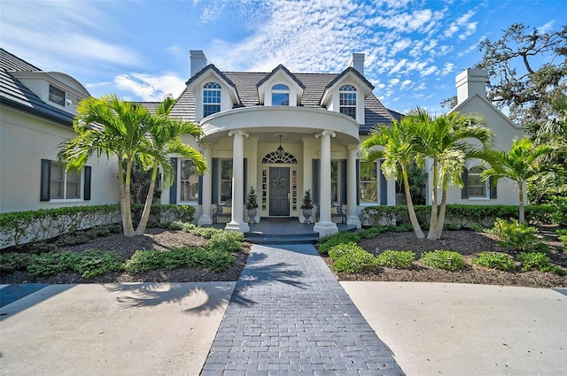 view of front of property featuring a porch, a chimney, and stucco siding