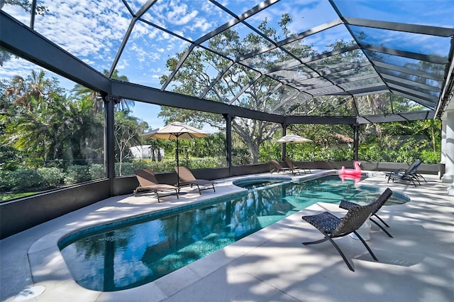 view of swimming pool featuring glass enclosure, a patio, and a pool with connected hot tub