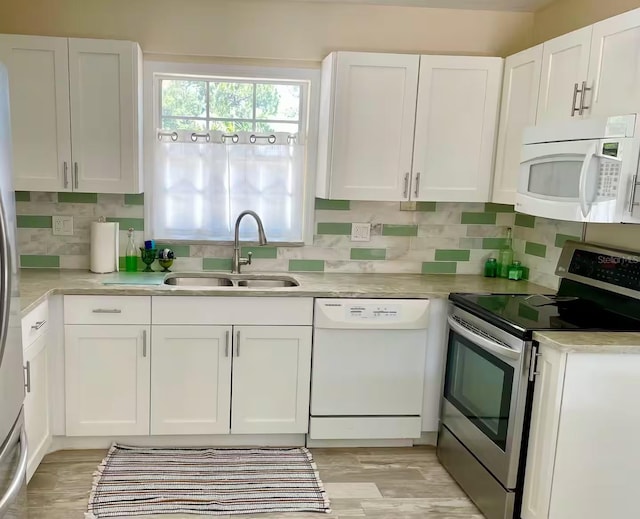 kitchen with sink, white appliances, white cabinets, and tasteful backsplash