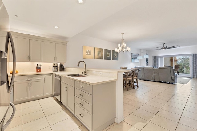 kitchen with light tile patterned floors, ceiling fan with notable chandelier, kitchen peninsula, and sink