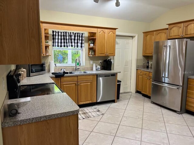 kitchen featuring appliances with stainless steel finishes, lofted ceiling, sink, light tile patterned flooring, and ceiling fan