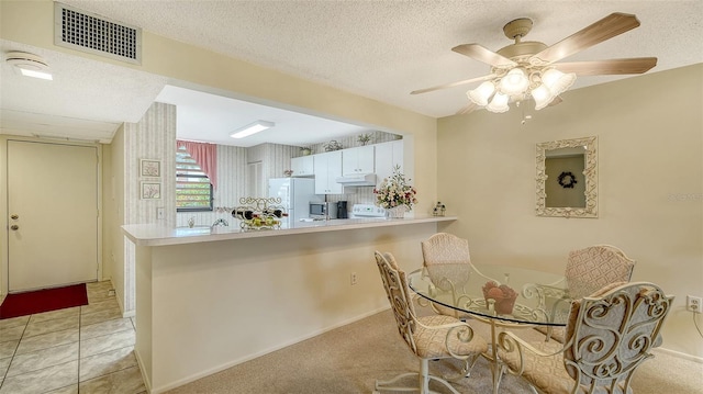 kitchen with a textured ceiling, white cabinets, white refrigerator, kitchen peninsula, and ceiling fan