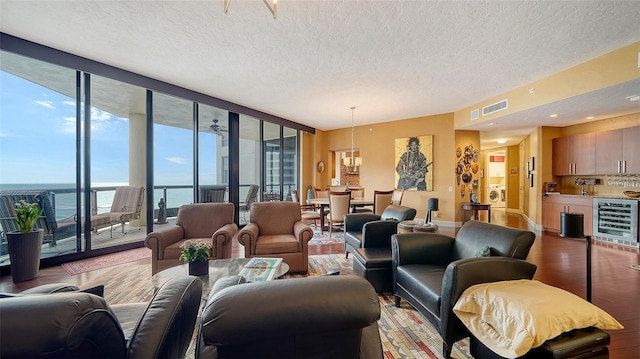 living room featuring a water view, light hardwood / wood-style floors, expansive windows, beverage cooler, and washer / dryer