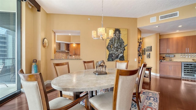 dining area featuring dark wood-type flooring, an inviting chandelier, wine cooler, and a textured ceiling