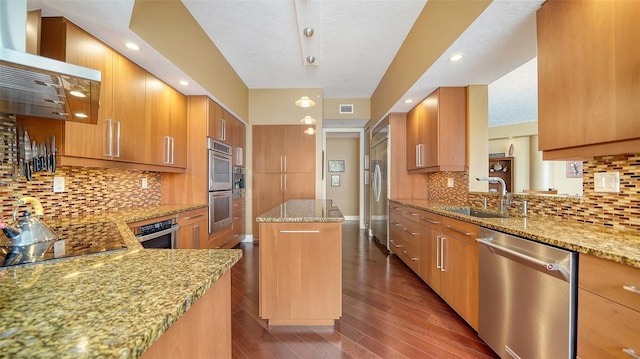 kitchen with sink, kitchen peninsula, light stone countertops, a kitchen island, and appliances with stainless steel finishes