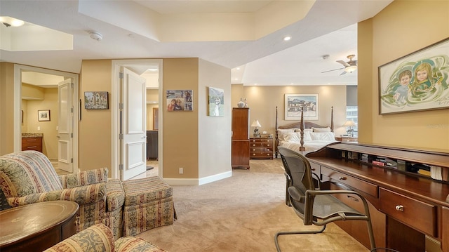 carpeted office space featuring ceiling fan and a tray ceiling