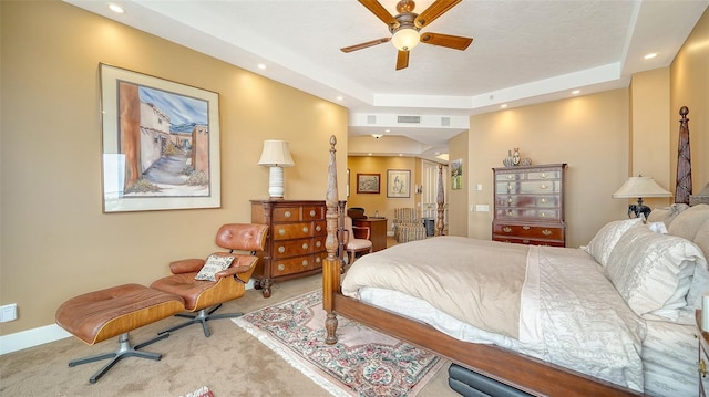 carpeted bedroom with ceiling fan and a tray ceiling