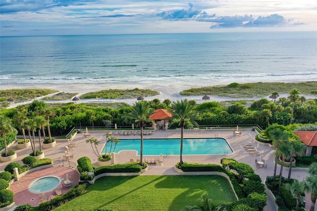 view of swimming pool with a patio area, a view of the beach, and a water view