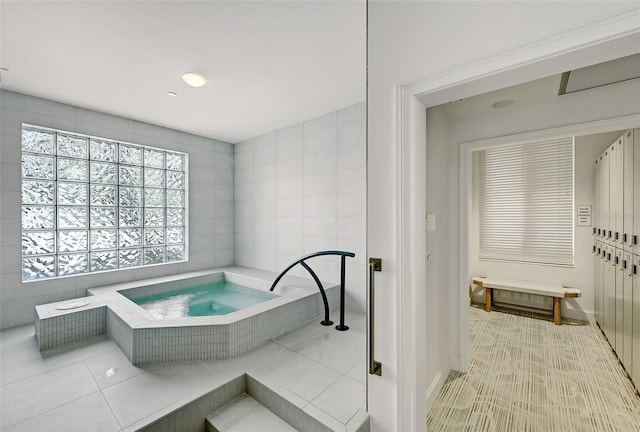 bathroom featuring tile patterned flooring and a relaxing tiled tub