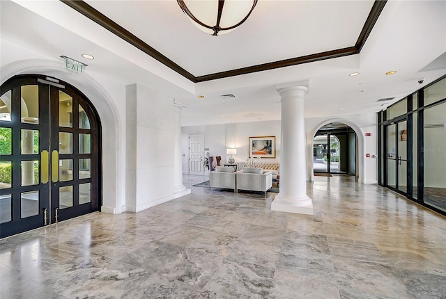 foyer featuring decorative columns, a raised ceiling, french doors, and crown molding