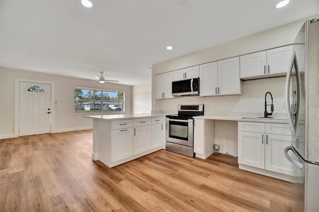 kitchen with sink, white cabinetry, kitchen peninsula, and appliances with stainless steel finishes