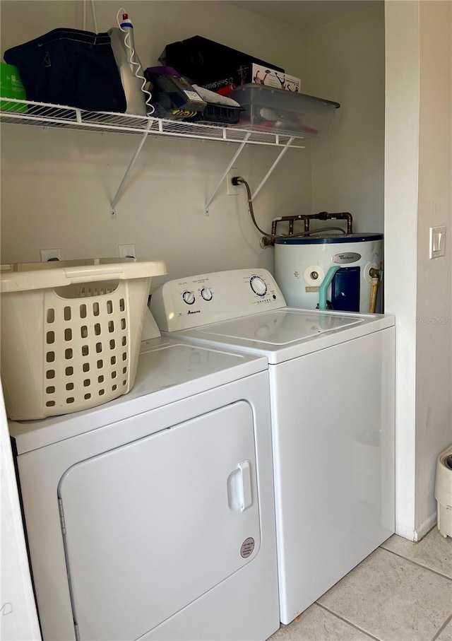 laundry area featuring water heater, washer and dryer, and light tile patterned flooring