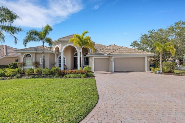 mediterranean / spanish-style home with a garage and a front lawn