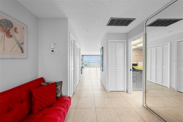 hallway featuring a textured ceiling and light tile patterned floors