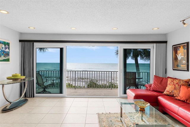 tiled living room with a textured ceiling, a healthy amount of sunlight, and a water view