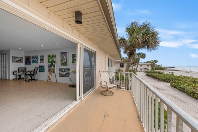 balcony featuring a view of the beach and a water view