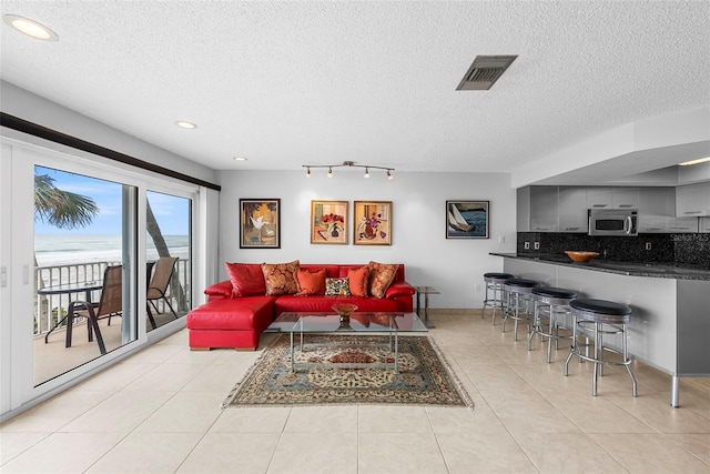 living room with a textured ceiling, light tile patterned flooring, and rail lighting