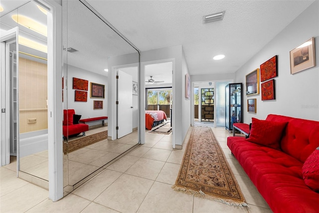 living room featuring a textured ceiling, ceiling fan, and light tile patterned flooring