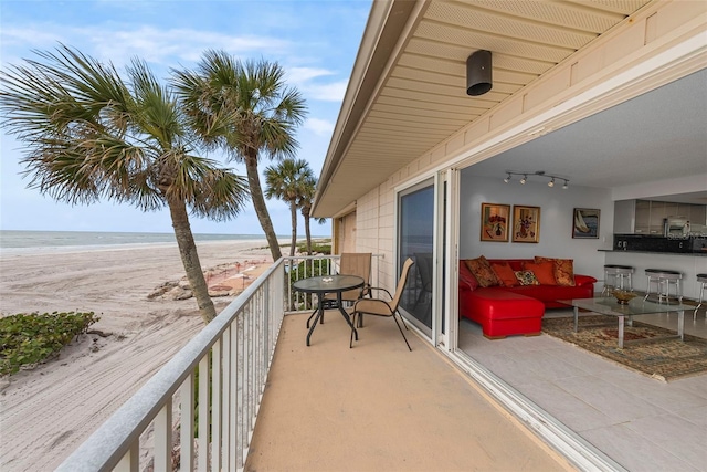 balcony featuring a water view, ceiling fan, and a beach view