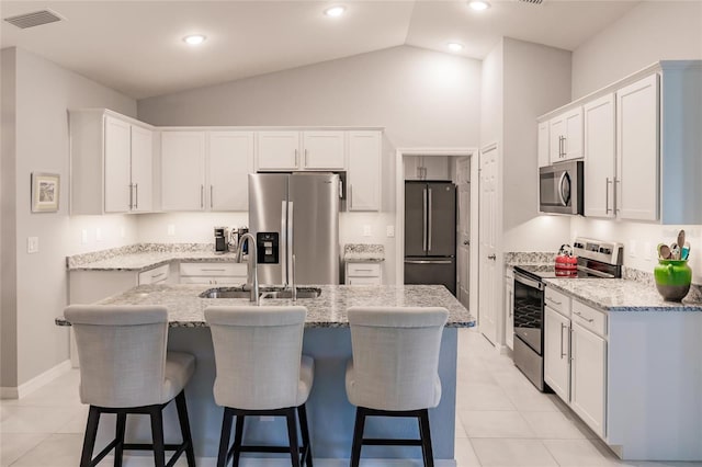 kitchen featuring white cabinetry, light tile patterned floors, stainless steel appliances, and an island with sink