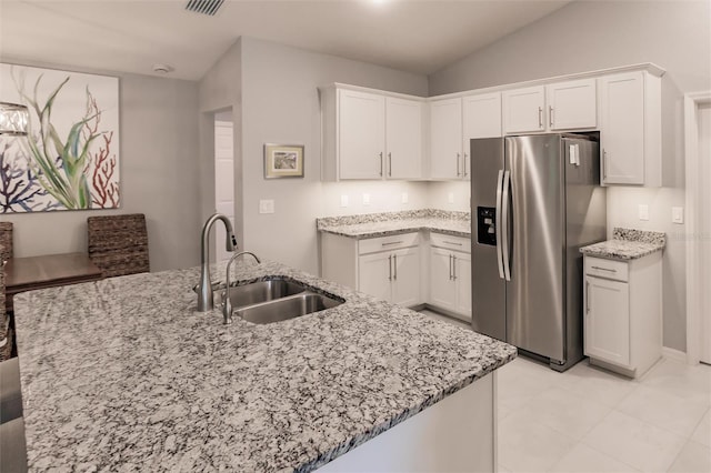 kitchen featuring stainless steel refrigerator with ice dispenser, white cabinets, light stone counters, and sink