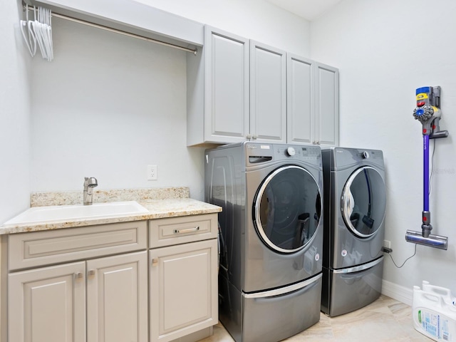 washroom with sink, washing machine and dryer, and cabinets