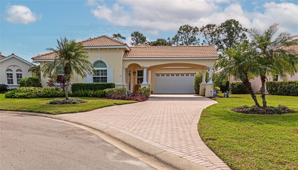 mediterranean / spanish home featuring a front yard and a garage