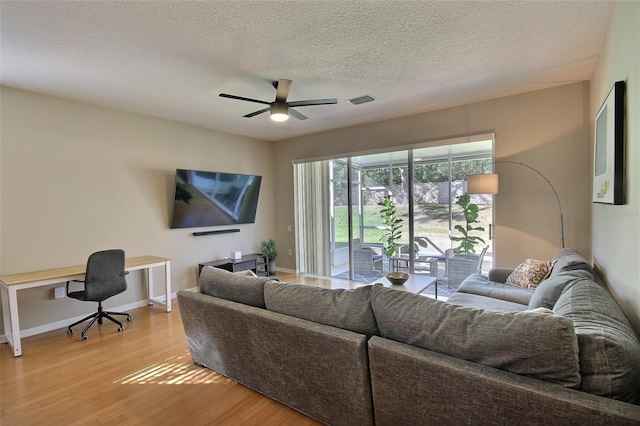 living room with light hardwood / wood-style floors, a textured ceiling, and ceiling fan